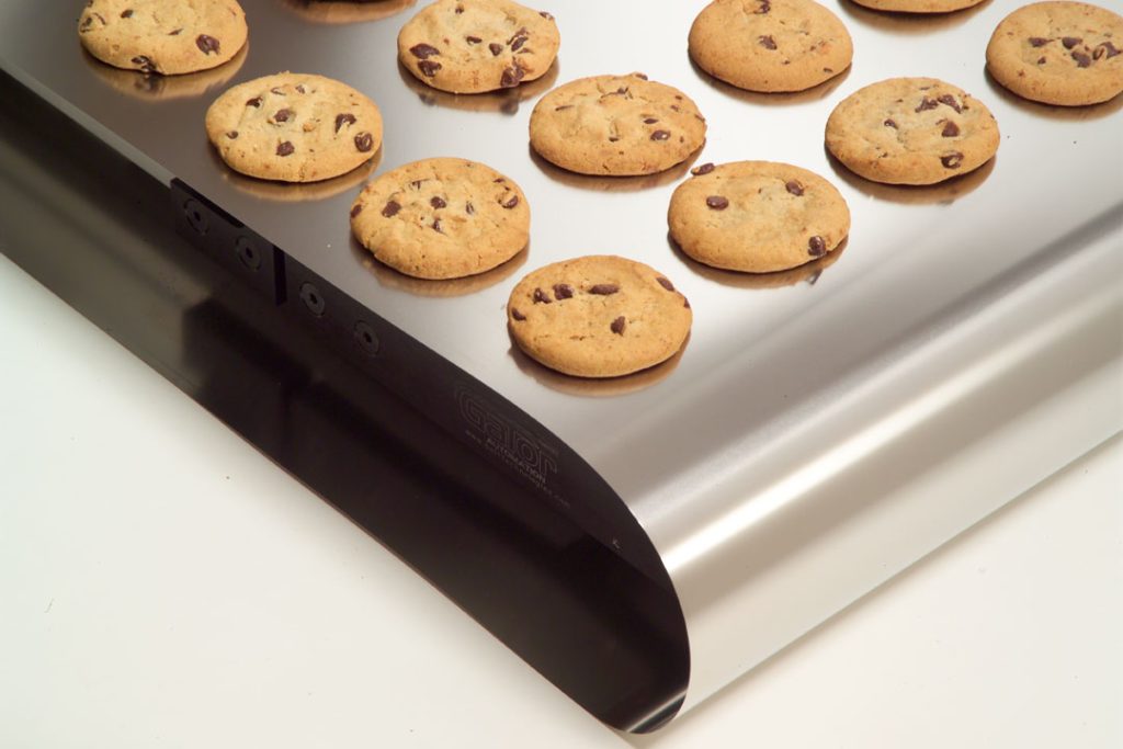 Chocolate chip cookies on a metal conveyor belt