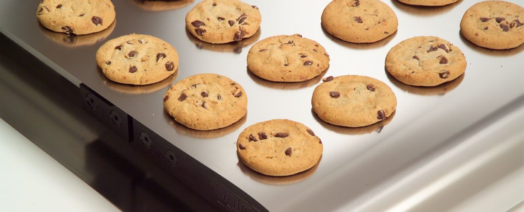 Chocolate chip cookies on a metal conveyor belt