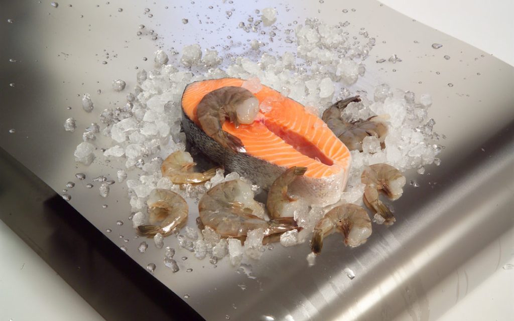 Salmon, shrimp and ice on a metal conveyor belt