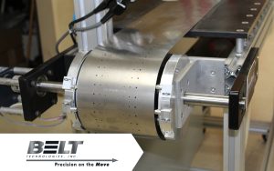 A close-up of a perforated steel belt in a vacuum conveyor system